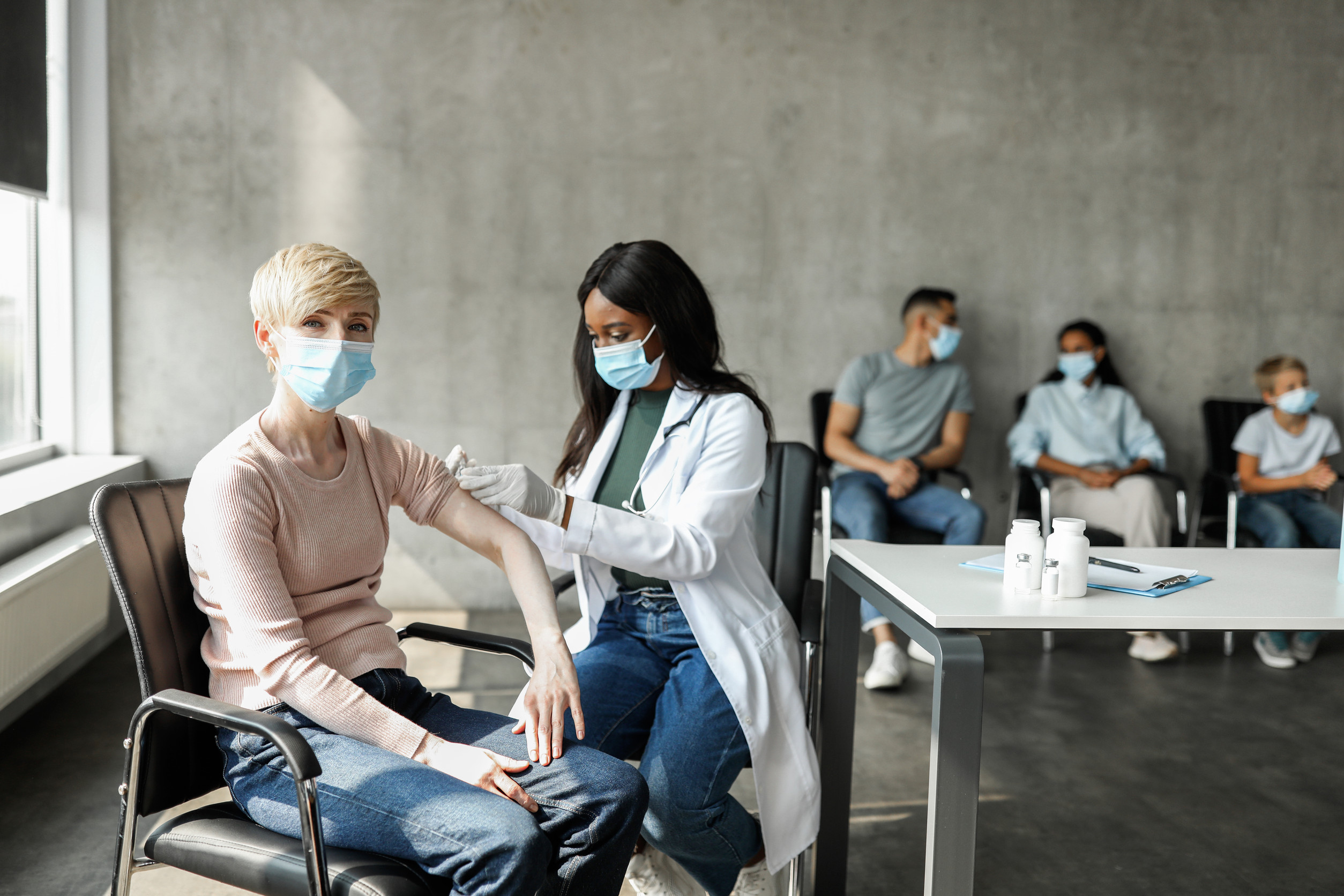 African american lady physician vaccinating mature lady against coronavirus