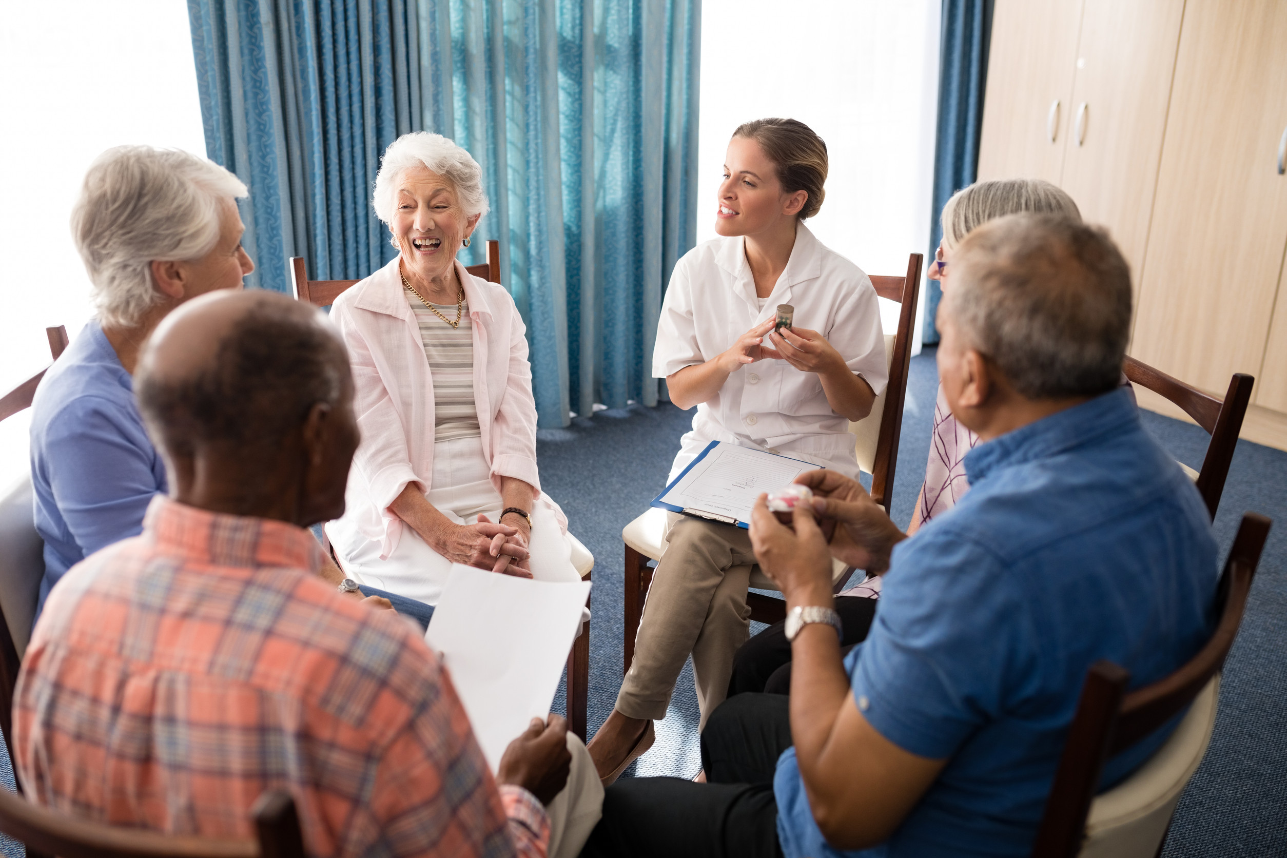 High angle view of smiling female doctor talking to seniors while sitting on chairs
