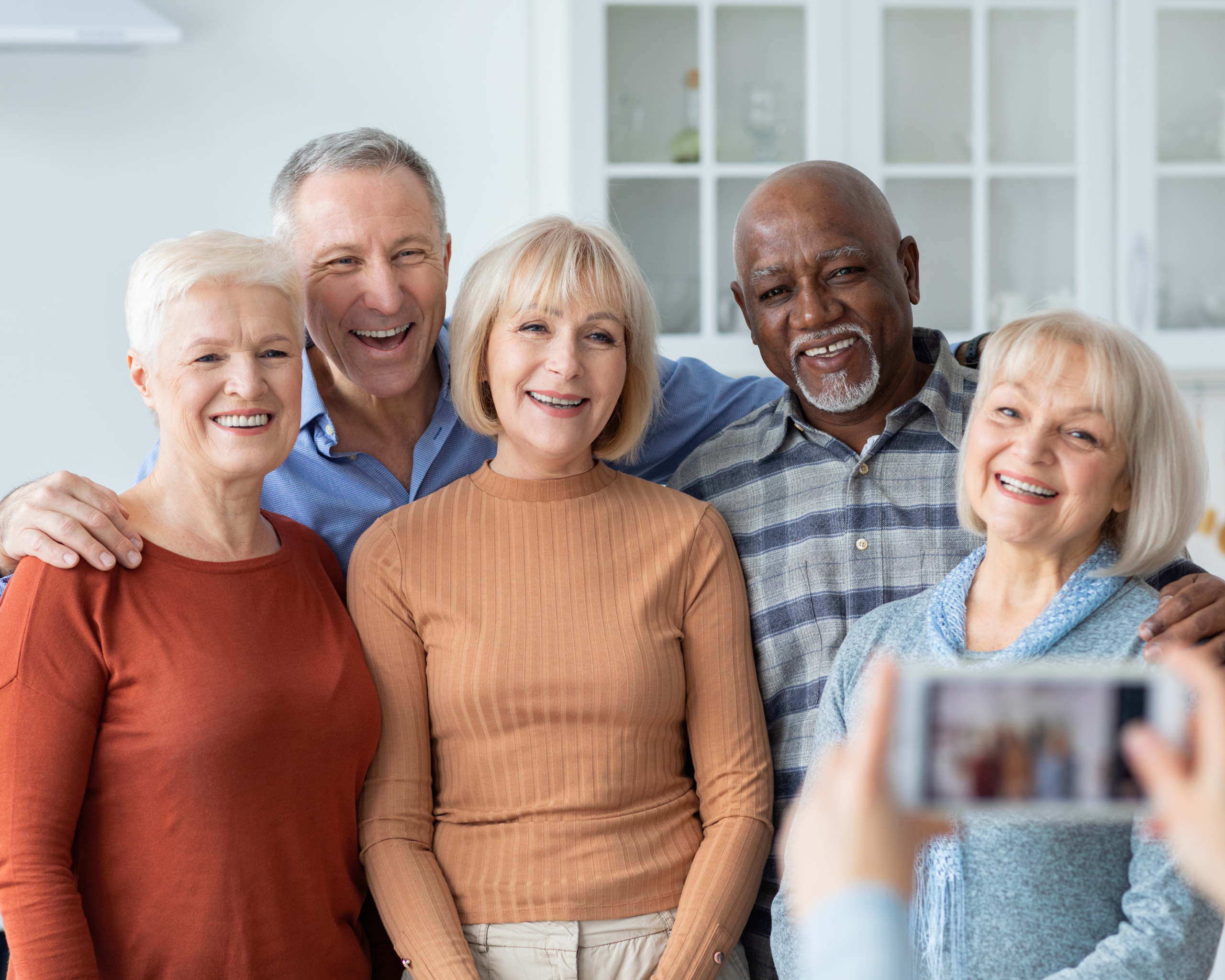 Unrecognizable person taking photo of multiracial group of senior people